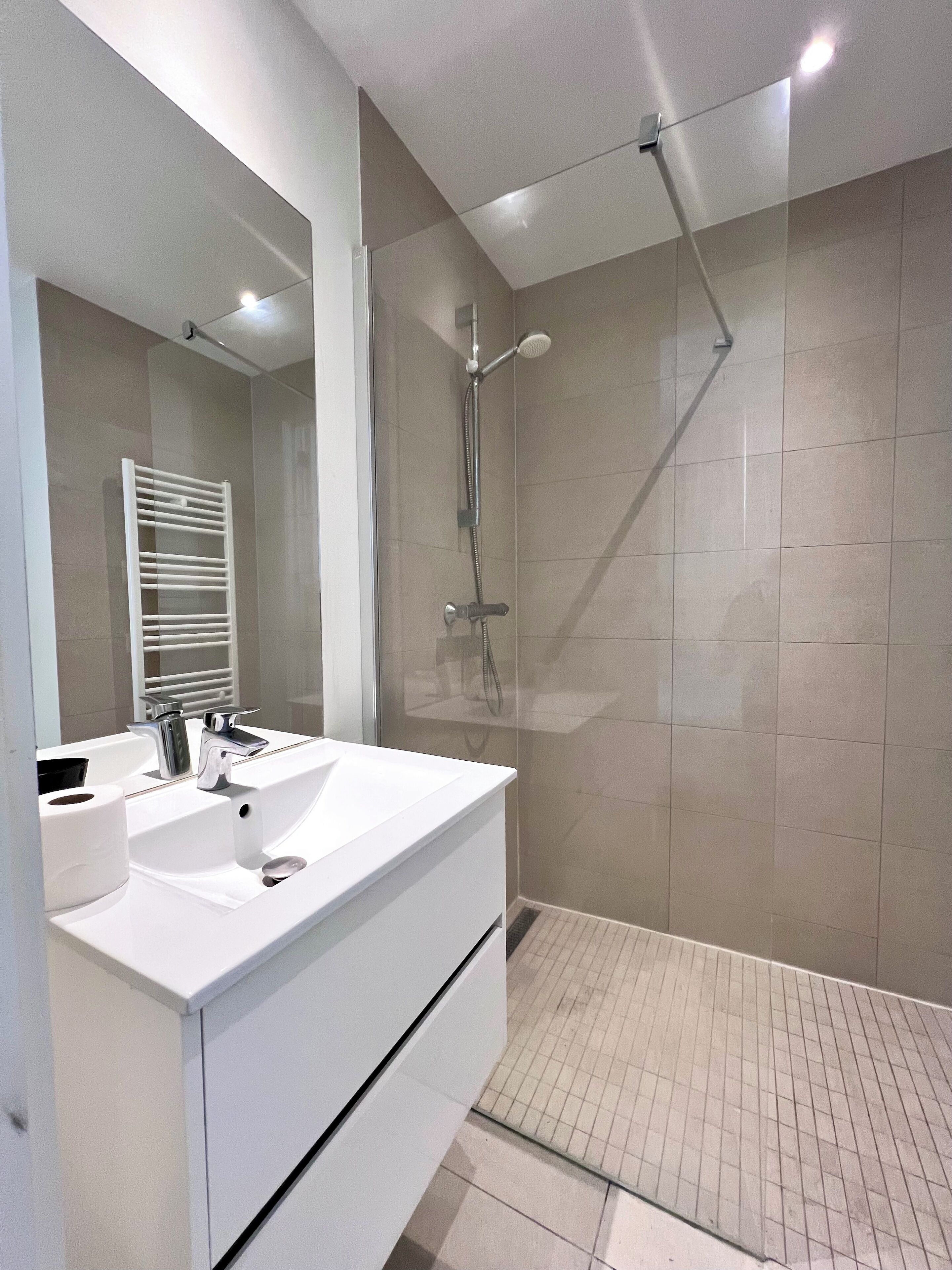 A modern bathroom with a white sink, mirror, and shower.