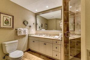 Une salle de bain comprenant des toilettes, un lavabo, un grand miroir et un espace douche.