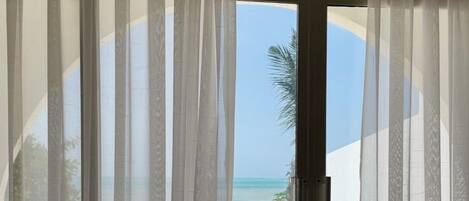 A room with a sliding glass door leading to a beach view.