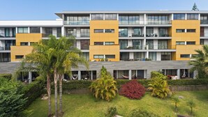 A multi-story hotel with balconies, a courtyard with palm trees, and a modern architectural design.