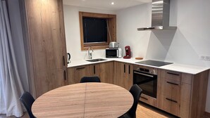 A modern kitchen with wooden cabinets, a round dining table, and black chairs.