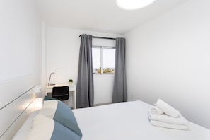 Ein modernes Hotelzimmer mit Bett, Schreibtisch und einem Fenster mit Vorhängen.