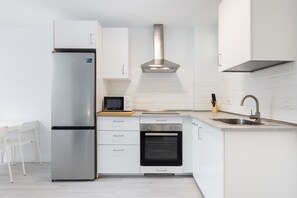 A modern kitchen with a stainless steel refrigerator, microwave, oven, and a built-in range hood.