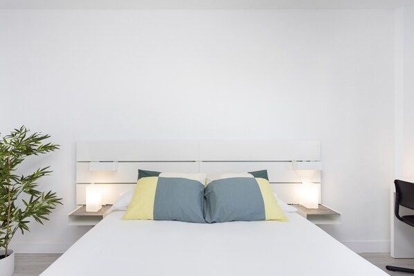 A modern hotel room with a large bed, bedside tables, a potted plant, and a chair. - Great sea view apt in Las Américas (Playa de Las Americas)