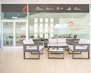 Un espace de bureau moderne comprenant un espace d’accueil, un coin salon et une entrée avec une porte en verre.