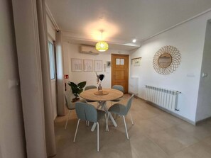 Un coin repas avec une table ronde et des chaises, un miroir fixé au mur et un radiateur.