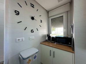 Une petite cuisine équipée d’un four à micro-ondes, d’une machine à café et de toilettes avec un distributeur de papier toilette.