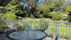 A round table with four chairs on an outdoor deck, surrounded by a metal railing. - Newly renovated, 3 bedroom, pet friendly unit. (Lorne)