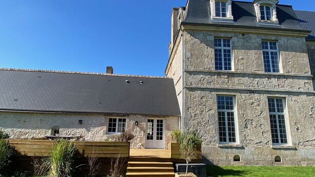 A stone building with a grey roof, a wooden deck, and a small garden area. - Spacious family home near Orleans, quiet with garden (Loury)
