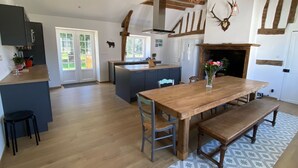 A spacious kitchen with a central island, wooden beams, a fireplace, and a dining area with a bench. - Spacious family home near Orleans, quiet with garden (Loury)