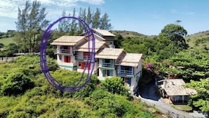 A two-story house with a balcony, surrounded by lush greenery and hills. - Hamarhavida (Imbituba)