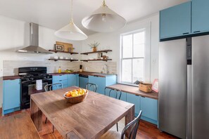 Eine moderne Küche mit blauen Schränken, einem Holztisch und einem Edelstahlkühlschrank.