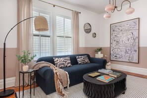 A living room with a dark blue sofa, a round black coffee table, a floor lamp, and a large abstract painting on the wall.