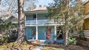A two-story house with a porch, a large tree in front, and a small garden. - Casa Azula (Atlanta)
