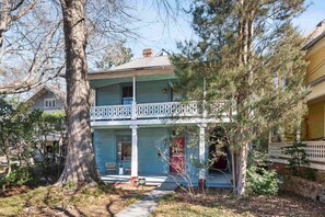 A two-story house with a porch, a large tree in front, and a small garden. - Casa Azula (Atlanta)