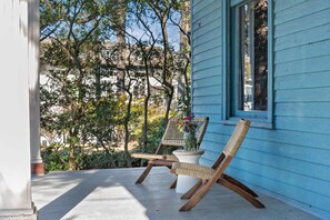 A porch with two wicker chairs and a potted plant.