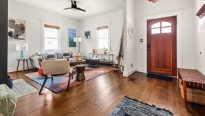 A spacious living room with hardwood floors, a sofa set, a coffee table, and a dining area. - Rustic Rouge (Atlanta)