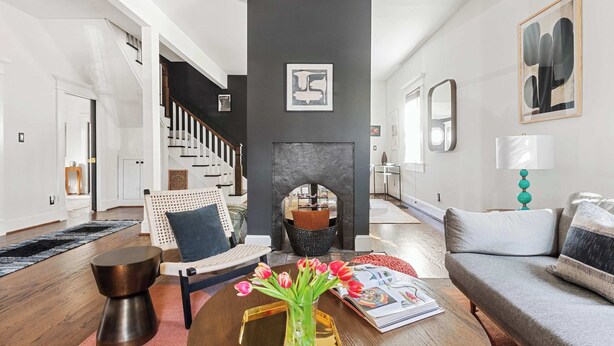 A modern living room with a fireplace, a staircase, and a sofa. - Rustic Rouge (Atlanta)