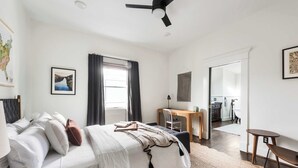 A modern bedroom with a bed, a desk, and a chair. There is a map on the wall and a picture of a landscape. - Rustic Rouge (Atlanta)