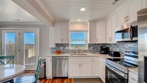 Una cocina moderna con armarios blancos, lavavajillas de acero inoxidable, un ventanal con vistas y un microondas empotrado.