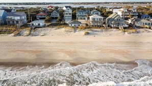 Zona residencial costera con casas frente a la playa, una playa de arena y olas del océano.