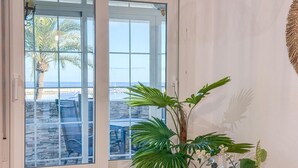 Una stanza con un'ampia finestra vista spiaggia, una pianta in vaso e un oggetto decorativo a parete.