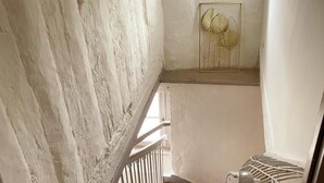 Un escalier étroit avec une rampe blanche, une main courante en métal et un élément décoratif en métal fixé au mur.