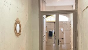 Une pièce avec un bureau en bois, une porte donnant sur une salle de bain et un miroir fixé au mur.