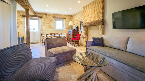 A cozy living room with a sofa, a glass coffee table, and a dining area with chairs and a table. - Charming lodge with parking, pets allowed, near Château de Clavières (Ardentes)