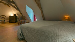 A bedroom with a large bed, a chair, a dresser, and a unique geometric light fixture. - Charming lodge with parking, pets allowed, near Château de Clavières (Ardentes)