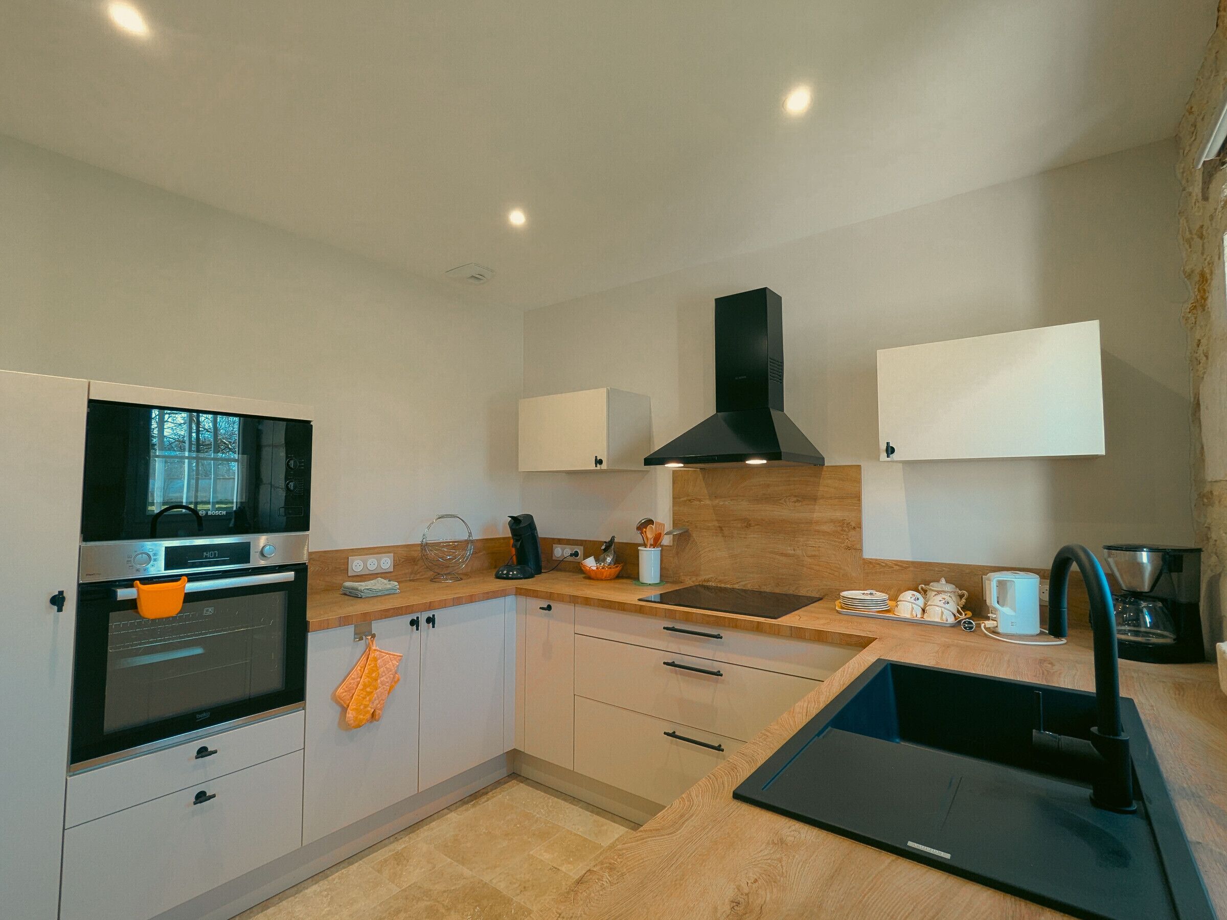 A modern kitchen with a Bosch oven, a black range hood, and a built-in dishwasher.