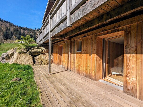 Situated in a natural setting, this cabin features a balcony and a large sliding door leading to a spacious interior.