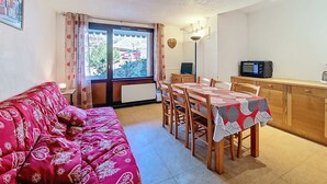 Ein gemütliches Wohnzimmer mit Sofa, Esstisch, Stühlen und einer Küchenzeile mit Mikrowelle.