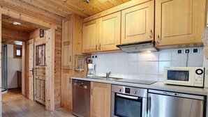 Una cocina compacta con armarios de madera, lavavajillas, estufa, horno y microondas.