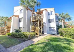 A modern two-story building with a central staircase, surrounded by well-maintained grass and palm trees. - Lagoon-View Unit Steps from Pool (Sarasota)