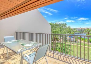 A balcony with a glass table and chairs, a view of greenery and buildings, and a clear sky. - Lagoon-View Unit Steps from Pool (Sarasota)