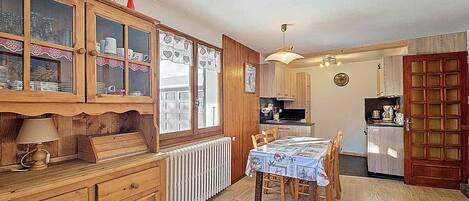 Une cuisine chaleureuse avec des meubles de rangement en bois, une table à manger avec des chaises et un réfrigérateur.