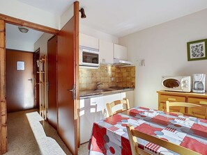 Enjoy meals in this cozy kitchen with a dining table for two, equipped with a stove, microwave, and coffee maker.