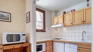 A compact kitchen with wooden cabinets, a microwave, a toaster, a dishwasher, and a sink. - Cozy Duplex in La Clusaz - 6 pax, pets allowed (La Clusaz)