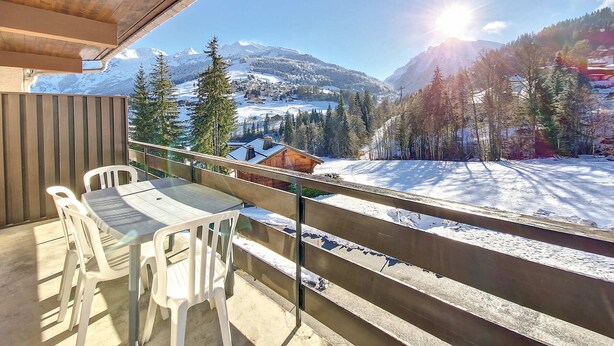 A balcony with a table and chairs, overlooking a snowy mountain landscape with a clear sky. - Cozy Duplex in La Clusaz - 6 pax, pets allowed (La Clusaz)