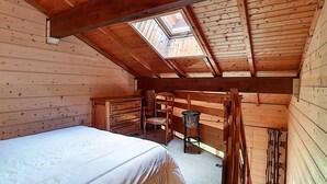 A wooden cabin bedroom with a skylight, a bed, a chair, and a small table. - Cozy Duplex 4 pers, La Clusaz, pets allowed (La Clusaz)