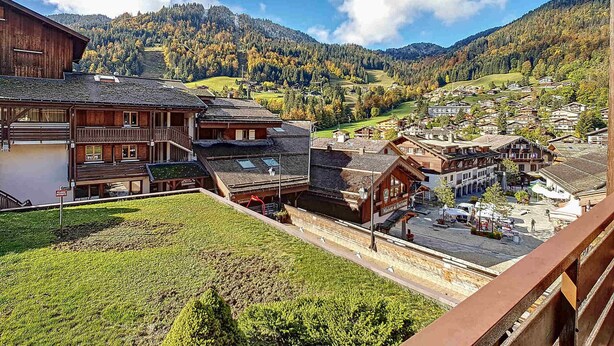 A traditional wooden building with a balcony, a small parking area, and a view of a mountainous landscape with a village below. - Cozy Duplex 4 pers, La Clusaz, pets allowed (La Clusaz)