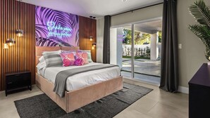 A modern bedroom with a bed, a neon sign, a large window, and a view of the outdoors. - THE GLAM PALMS (MountainViews/Sauna/EVCharger/BBQ/Golf/HeatedPool) (Palm Springs)