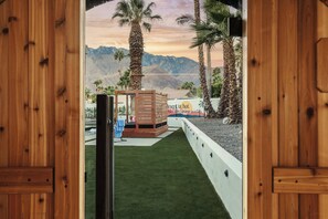 A wooden door frame with a view of a desert landscape, palm trees, and a building with a sign that reads 'Desert is hot.'