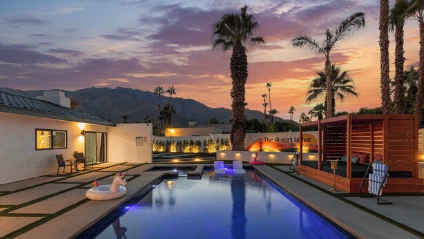 A swimming pool with a sunset view, palm trees, and a wooden structure with a sign. - THE GLAM PALMS (MountainViews/Sauna/EVCharger/BBQ/Golf/HeatedPool) (Palm Springs)