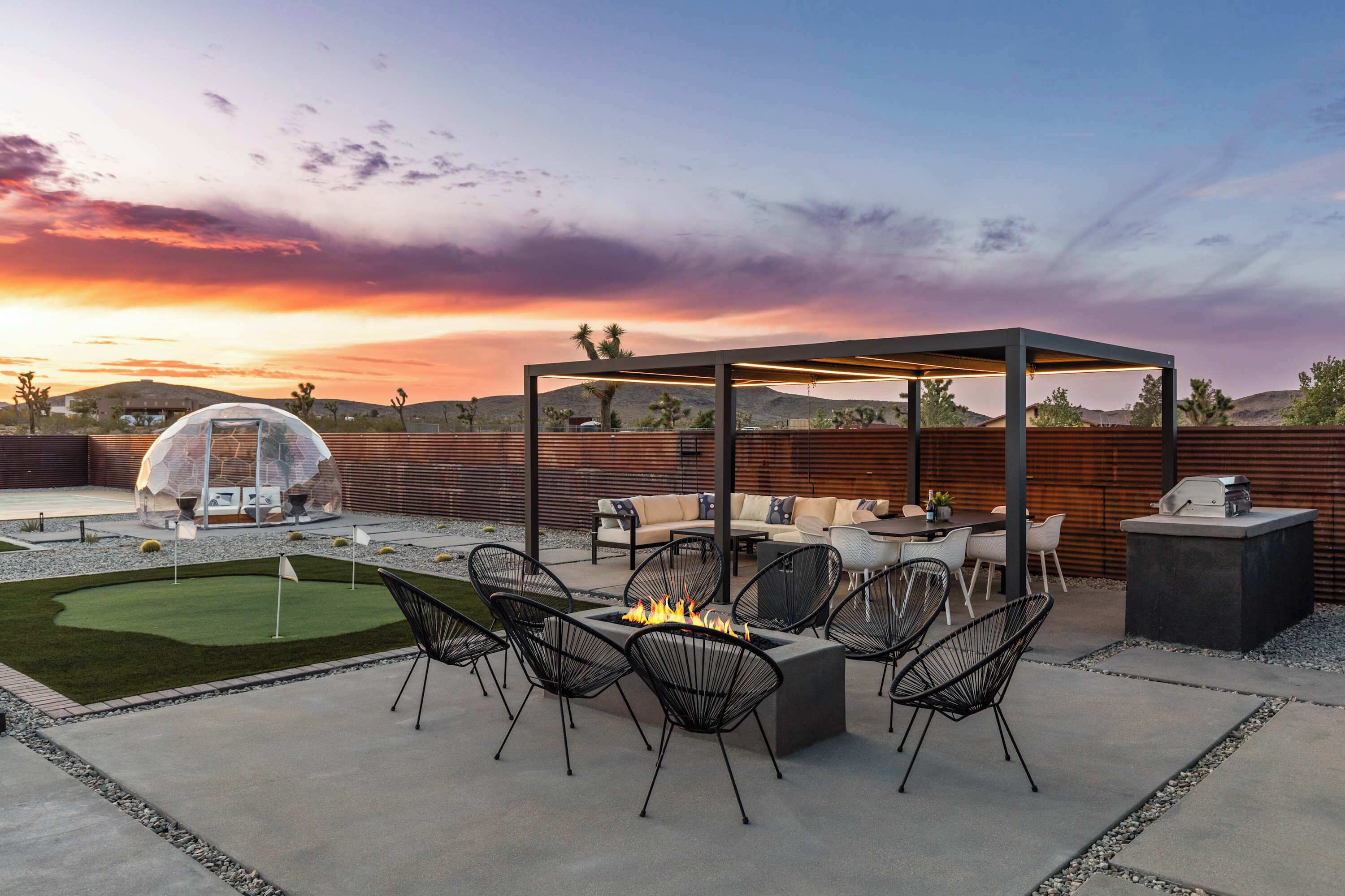 An outdoor patio with a fire pit, seating, and a pergola.
