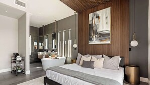 Une chambre moderne avec un grand lit, une salle de bain avec une baignoire et un coin repas avec une table et des chaises.