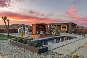 A modern outdoor pool area with a wooden pergola, seating, and a clear view of the pool.