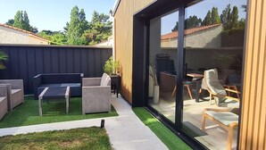 Um pátio moderno ao ar livre com área de refeições, churrasqueira e um espaço para relaxar.