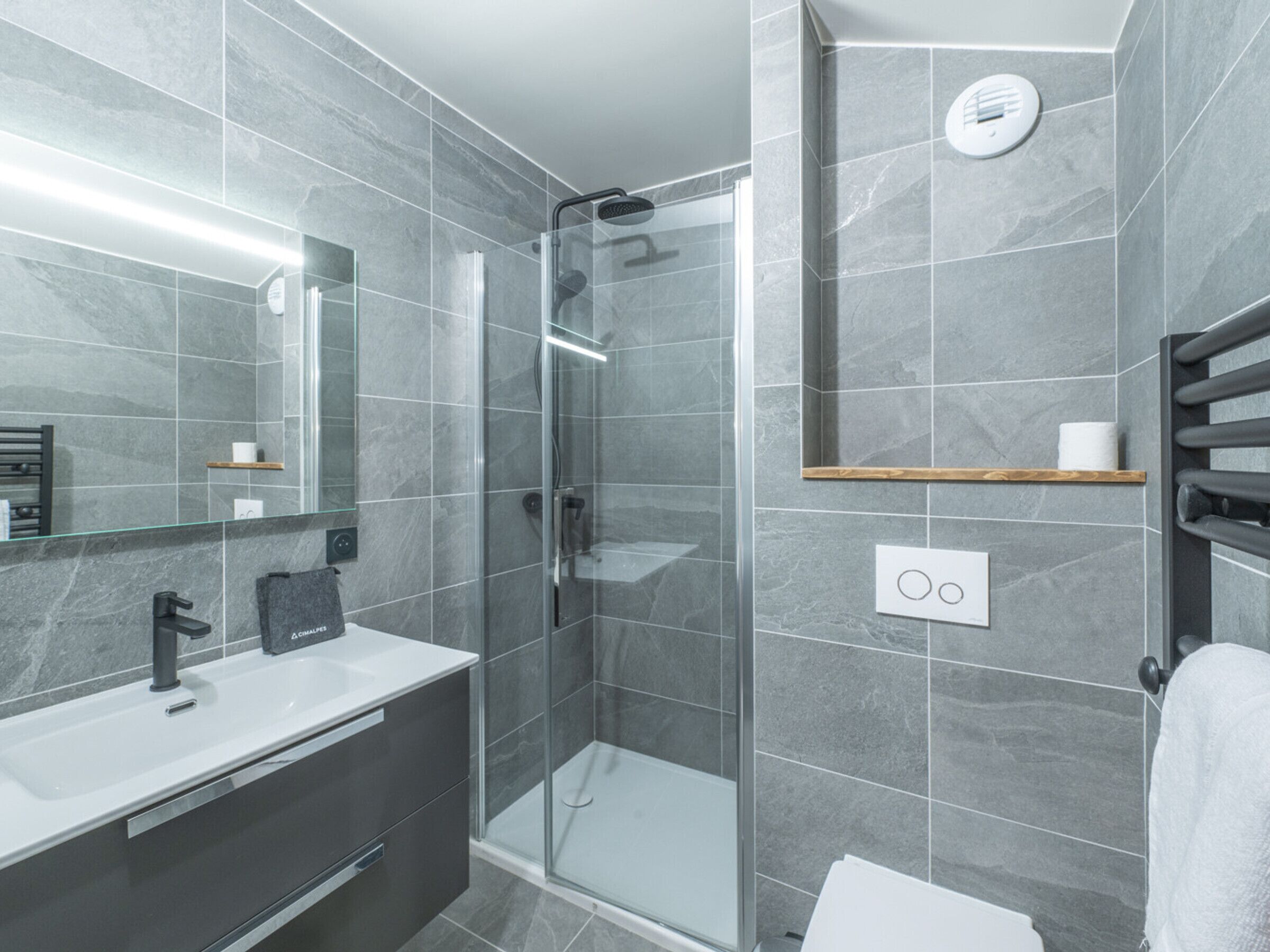 A modern bathroom with a glass-enclosed shower, a white sink, and a mirror.